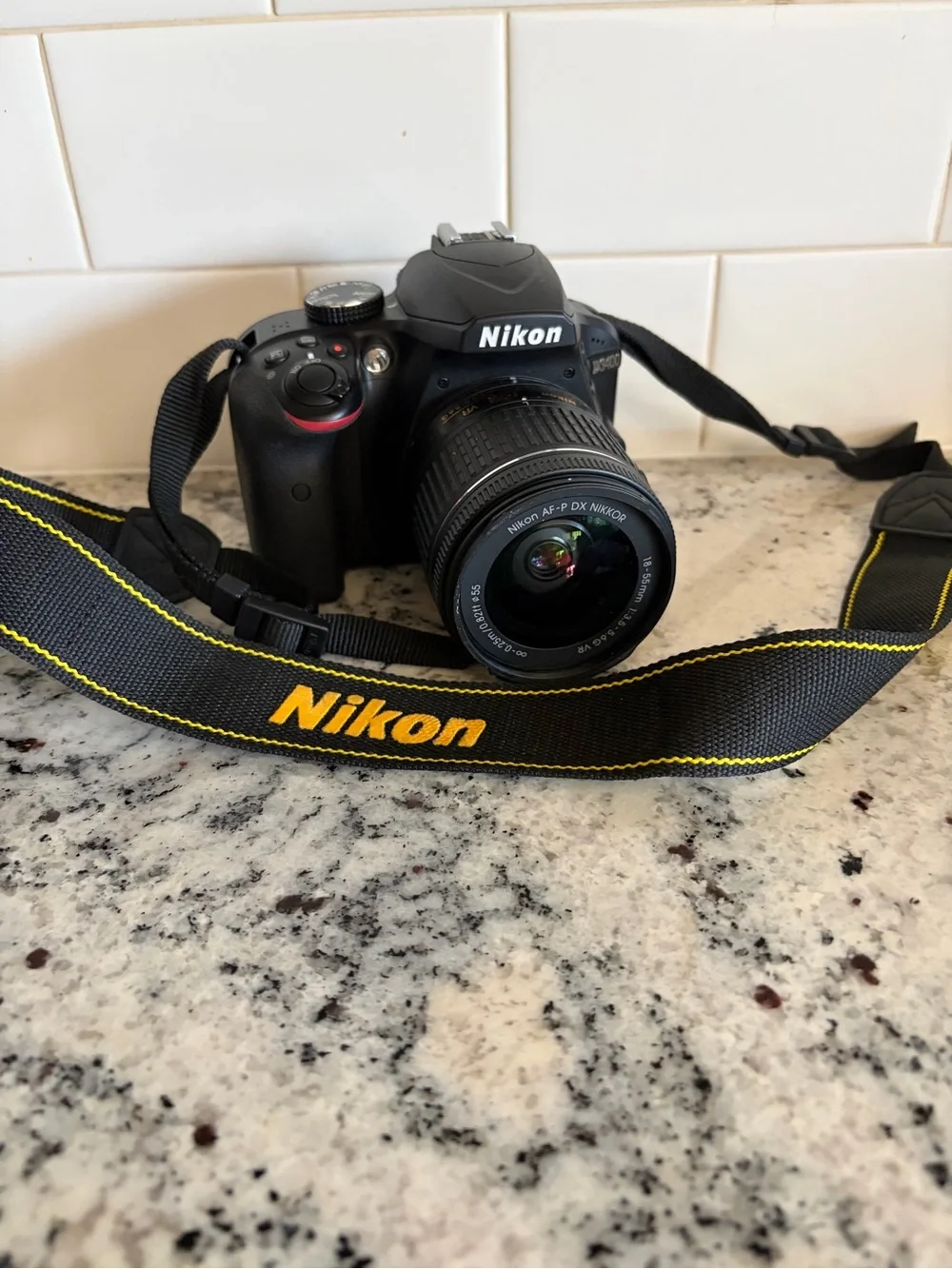 Nikon Black DSLR with AF-P DX NIKKOR Lens and Yellow-Accented Strap